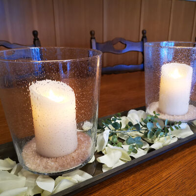 Bild vergrößern: Blick in den Sitzungssaal, im Vordergrund eine zwei große Kerzen im Glas umringt von weißen Rosenblättern